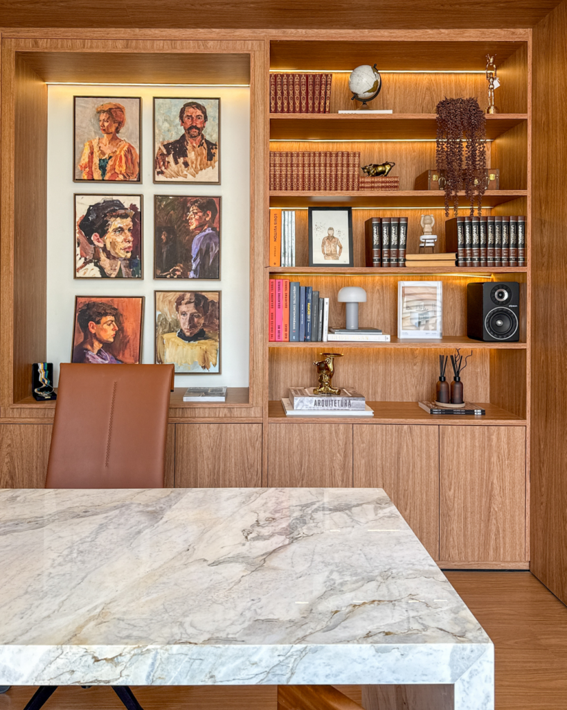 Estante Casttini em marcenaria sob medida com iluminação de destaque para livros e objetos decorativos em escritório de design.