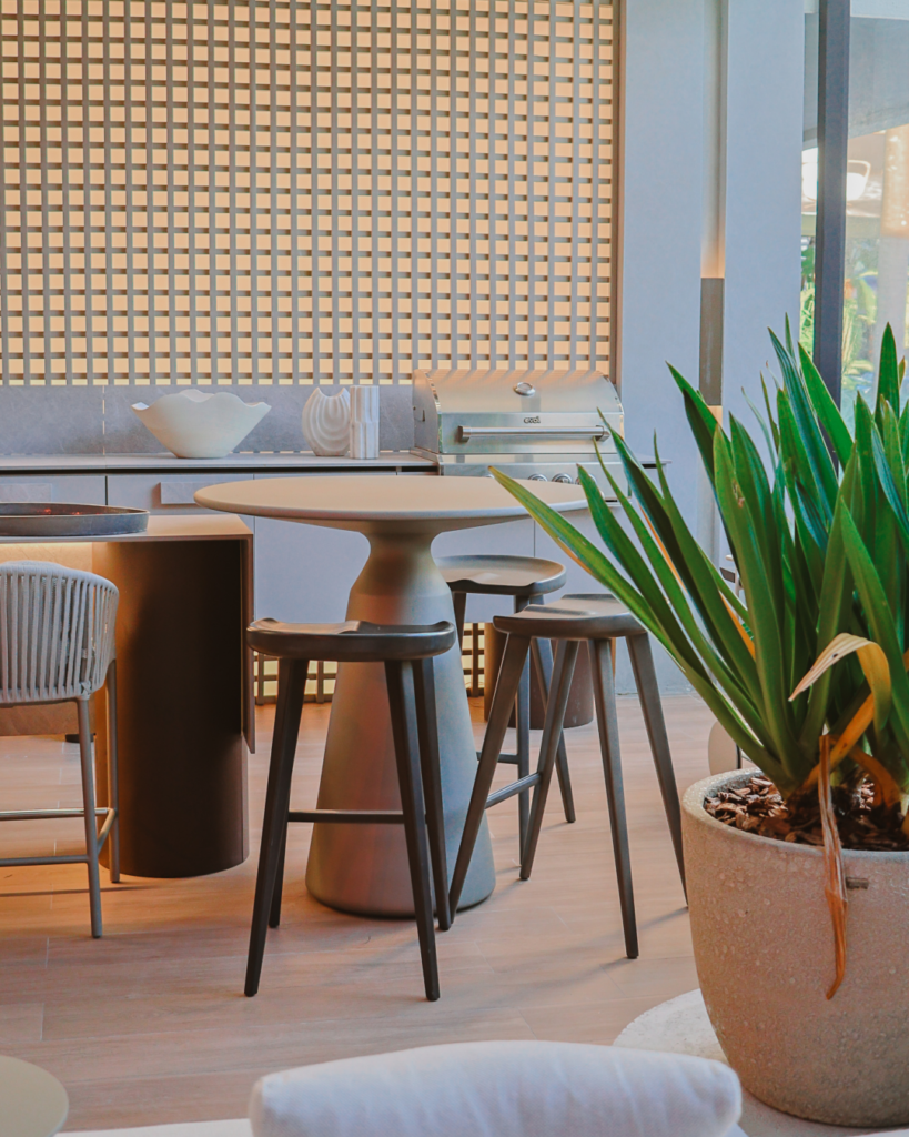 Ambiente gourmet planejado pela Casttini com iluminação equilibrada, painel ripado ao fundo, mesa bistrô e decoração com plantas, criando um espaço acolhedor e funcional.